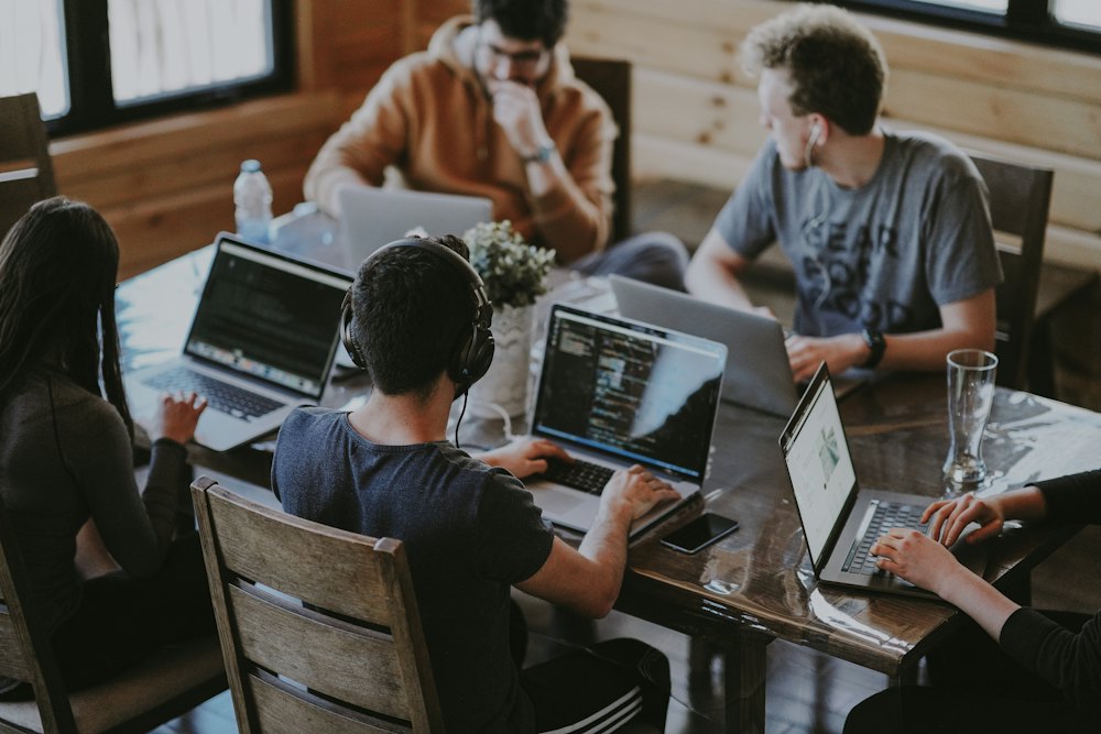 A team of students coding on laptops around a table